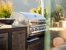 INTERIOS. Dein Interior-Design-Studio. Moderner Gasgrill im Außenbereich mit Pfanne und Kochutensilien bei Sonnenschein