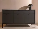 INTERIOS. Dein Interior-Design-Studio. Schwarzes Sideboard mit geriffelter Front und Tischlampe vor rosafarbener Wand