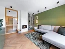 INTERIOS. Dein Interior-Design-Studio. Modernes Wohnzimmer mit grauem Sofa, grünem Akzentwand und kleinem Kamin