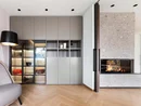 INTERIOS. Dein Interior-Design-Studio. Moderner Wohnraum mit grauem Schrank, beleuchteten Vitrinen und Kamin
