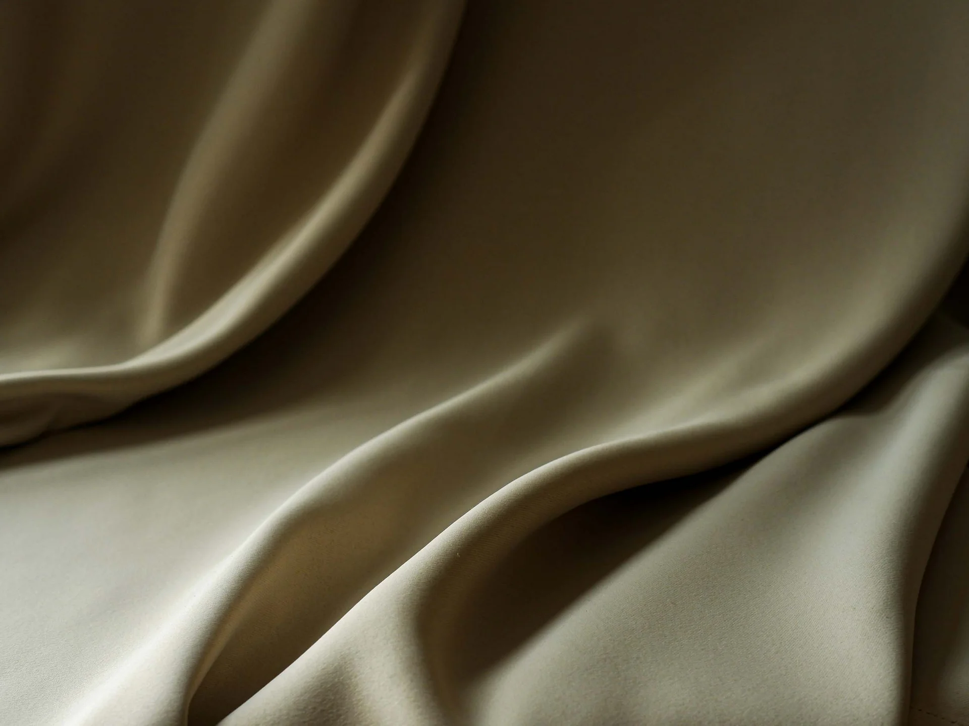 INTERIOS. Dein Interior-Design-Studio. Nahaufnahme von beige gefaltetem Stoff mit weichen Falten