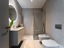 INTERIOS. Dein Interior-Design-Studio. Modernes Badezimmer mit Dusche, Toilette, Bidet und beleuchtetem Spiegel