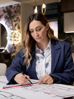 Grundrissplanung und Innenarchitektur Frau markiert technische Zeichnungen mit Lineal in modernem Büro