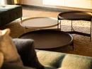INTERIOS. Dein Interior-Design-Studio. Drei runde Tische unterschiedlicher Höhe auf einem Teppich neben einem Sofa