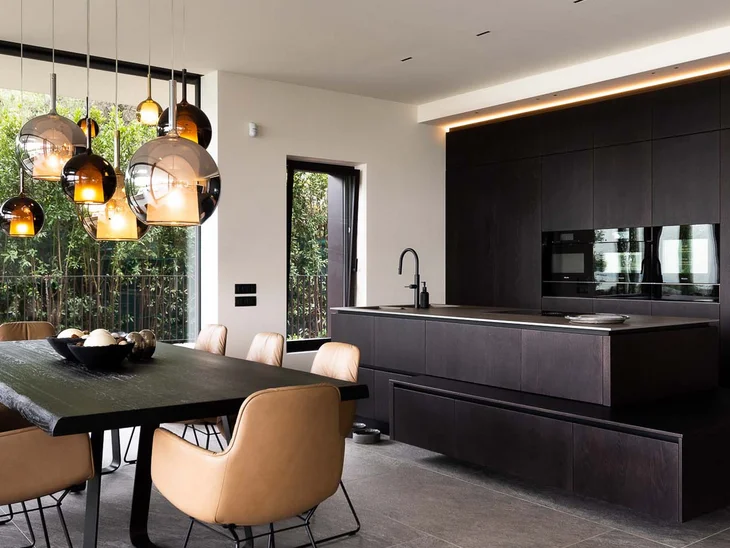 INTERIOS. Dein Interior-Design-Studio. Moderner Essbereich mit braunen Stühlen und dunkler Holzküche