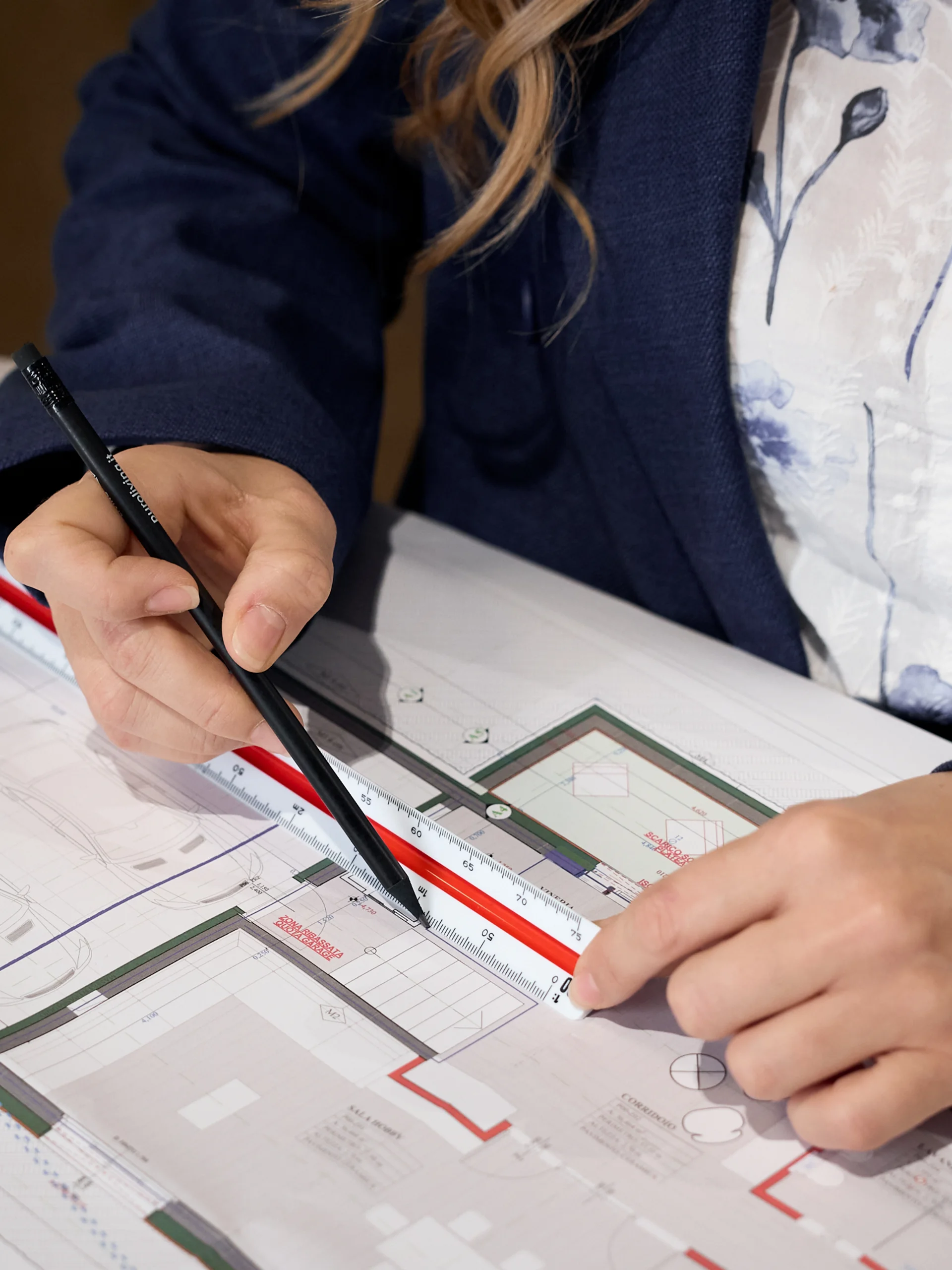 INTERIOS. Dein Interior-Design-Studio. Person misst Architekturplan mit Lineal und Stift