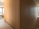 INTERIOS. Dein Interior-Design-Studio. Moderner Innenraum mit großem Holzpaneel und Treppe