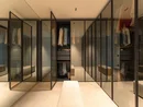 INTERIOS. Dein Interior-Design-Studio. Begehbarer Kleiderschrank mit Glasfronten, Kleidung und Sitzbank
