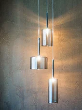 INTERIOS. Dein Interior-Design-Studio. Drei moderne hängende Glaskolbenlampen an einer dunklen Wand