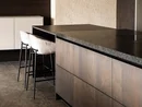 INTERIOS. Dein Interior-Design-Studio. Moderne Kücheninsel mit Holzfronten und zwei gepolsterten Barhockern