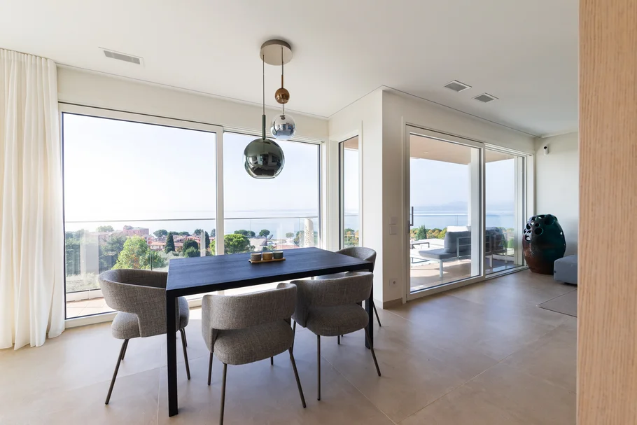 INTERIOS. Dein Interior-Design-Studio. Moderner Essbereich mit Tisch, Stühlen und Panoramablick auf die Natur