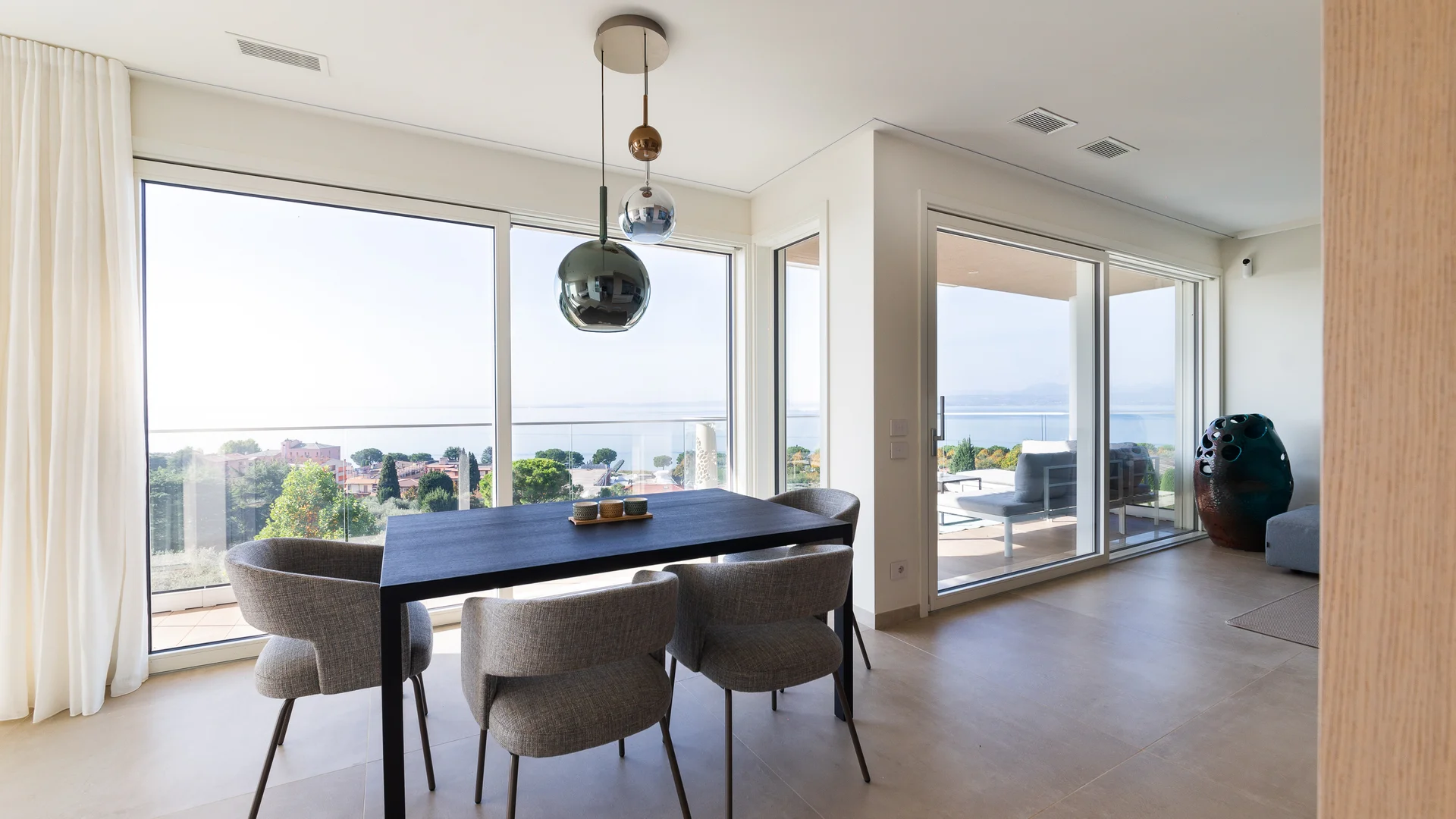 INTERIOS. Dein Interior-Design-Studio. Moderner Essbereich mit Tisch, Stühlen und Panoramablick auf die Natur