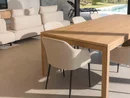 INTERIOS. Dein Interior-Design-Studio. Heller Wohnbereich mit Holztisch, Polsterstühlen, Sofas und Blick auf den Pool