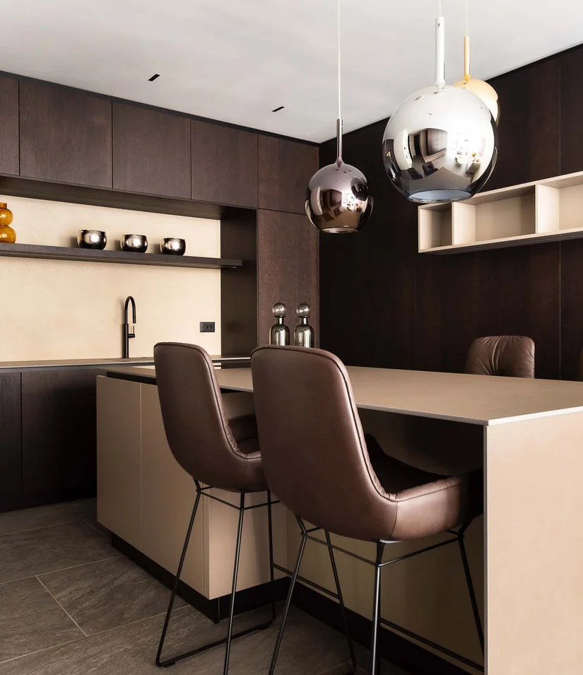 INTERIOS. Dein Interior-Design-Studio. Moderne Küche mit dunklen Holzschränken und zwei braunen Barhockern