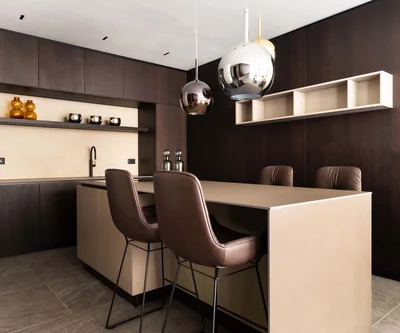 INTERIOS. Dein Interior-Design-Studio. Moderne Küche mit dunklen Holzschränken und zwei braunen Barhockern