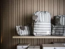 INTERIOS. Dein Interior-Design-Studio. Gestreifte Taschen mit Herzanhängern auf einem Holzregal vor Holzwand