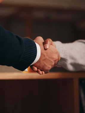 Unverbindliches Erstgespräch Zwei Personen beim Händedruck im inneren Raum