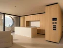 INTERIOS. Dein Interior-Design-Studio. Modernes Wohnzimmer mit heller Holzküche, Kücheninsel und rundem Fenster