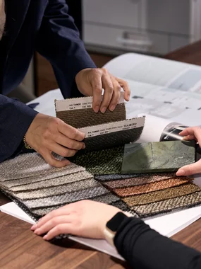 Farb- und Materialkonzept Zwei Personen wählen Stoffmuster und Farbmuster an einem Holztisch aus