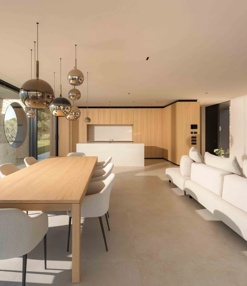 INTERIOS. Dein Interior-Design-Studio. Modernes Wohnzimmer mit Esstisch, weißem Sofa und offener Küche