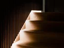 INTERIOS. Dein Interior-Design-Studio. Dunkle Holztreppe mit integrierter Beleuchtung an der Wand