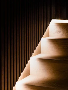 Einrichtungs- und Beleuchtungsplanung Dunkle Holztreppe mit integrierter Beleuchtung an der Wand