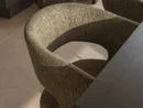 INTERIOS. Dein Interior-Design-Studio. Gepolsterter Esszimmerstuhl neben einem Tisch und einer Dekovase