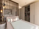 INTERIOS. Dein Interior-Design-Studio. Modernes Schlafzimmer mit Doppelbett, Holzlamellenwand und Einbauschrank