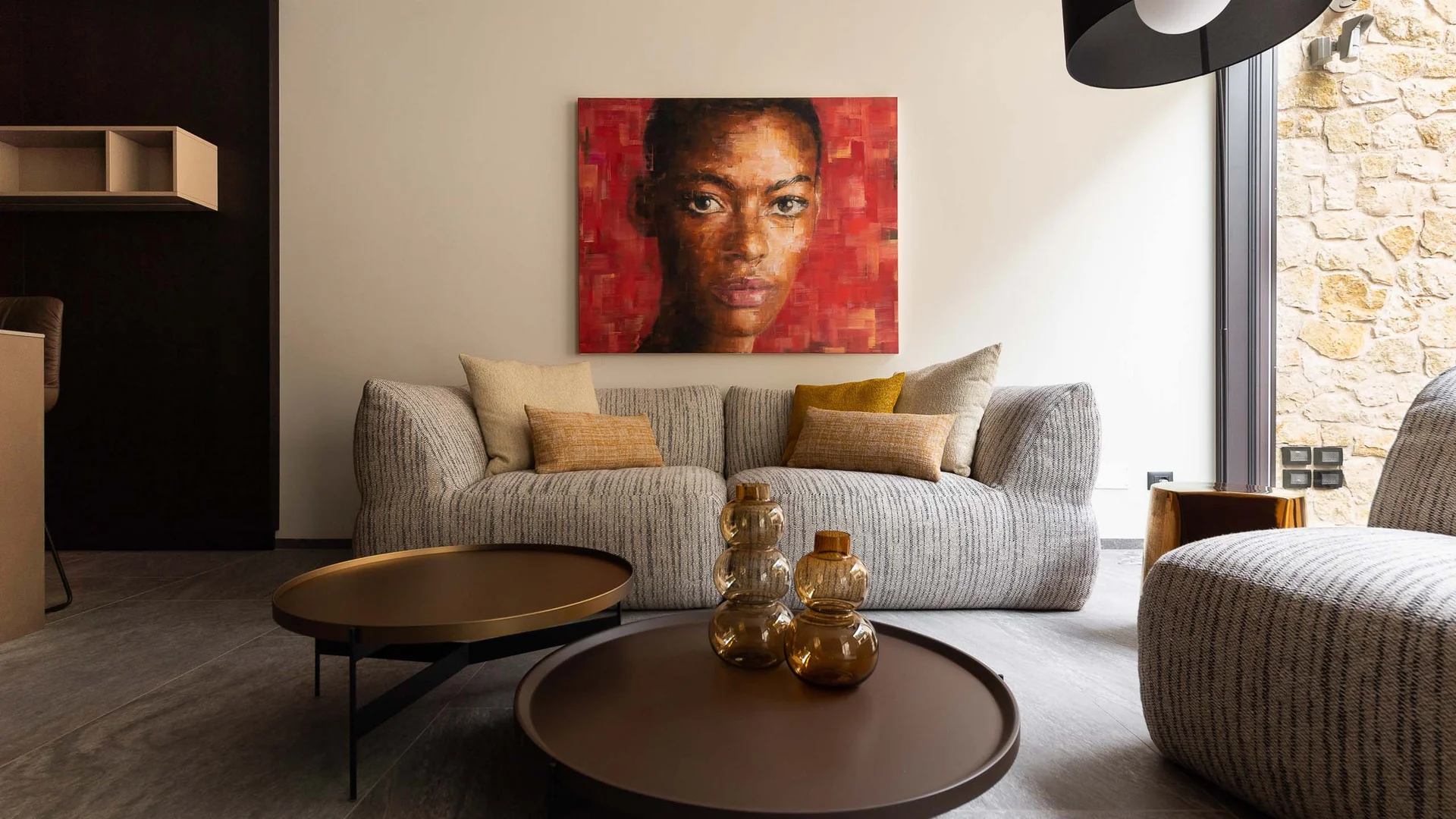 INTERIOS. Dein Interior-Design-Studio. Modernes Wohnzimmer mit grauem Sofa, braunen Tischen und Porträt an roter Wand