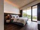 INTERIOS. Dein Interior-Design-Studio. Modernes Schlafzimmer mit großem Bett und Balkon mit Blick auf grüne Hügel