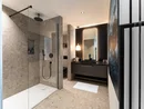INTERIOS. Dein Interior-Design-Studio. Modernes Badezimmer mit begehbarer Dusche, grauen Fliesen und beleuchtetem Spiegel