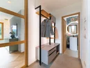 INTERIOS. Dein Interior-Design-Studio. Moderner Flur mit Garderobe und Blick ins Badezimmer mit rundem Spiegel