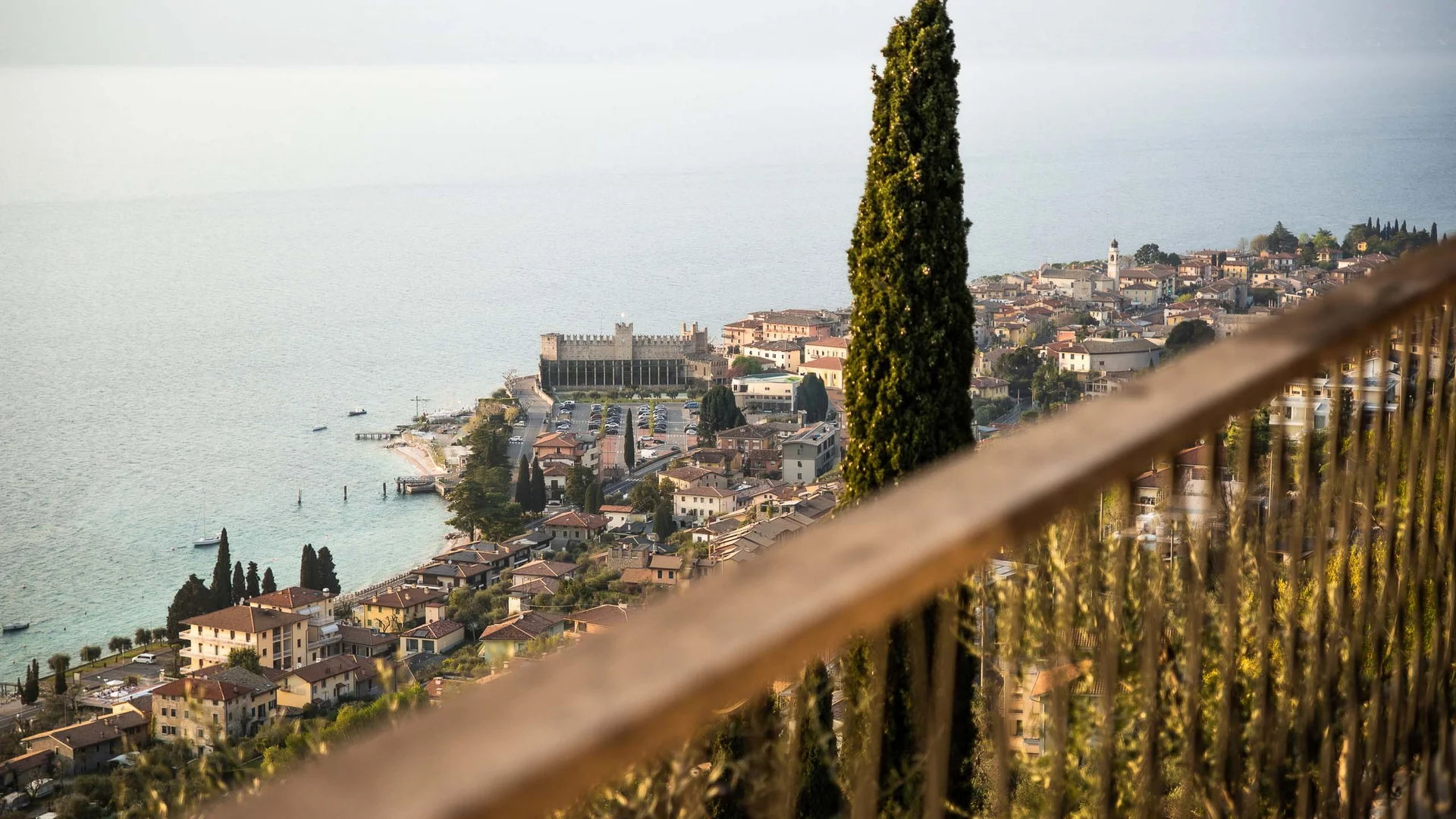 INTERIOS. Dein Interior-Design-Studio. Blick auf den Gardasee und das Städtchen mit hoher Zypresse im Vordergrund