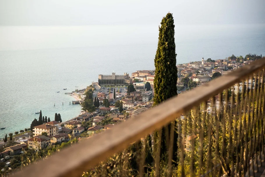 INTERIOS. Dein Interior-Design-Studio. Blick auf den Gardasee und das Städtchen mit hoher Zypresse im Vordergrund