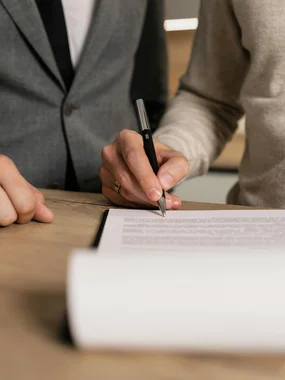 Exklusive Verkaufsunterlagen Person unterschreibt Dokument während andere Person danebensteht