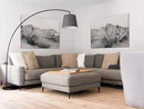 INTERIOS. Dein Interior-Design-Studio. Gemütliche Sitzecke mit grauem Ecksofa, Hocker, Stehlampe und Bergbildern