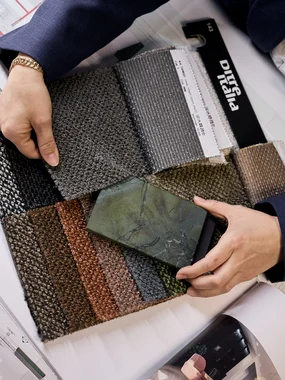 Produkt- und Ausstattungskonzepte Person hält Stoffmuster und eine Steinprobe über Bauplänen