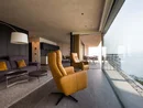 INTERIOS. Dein Interior-Design-Studio. Modernes Wohnzimmer mit Ledersesseln und Meerblick durch Panoramafenster