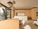 INTERIOS. Dein Interior-Design-Studio. Offener Wohn- und Essbereich mit Holztisch, Kücheninsel, Hängeleuchten und weißem Sofa
