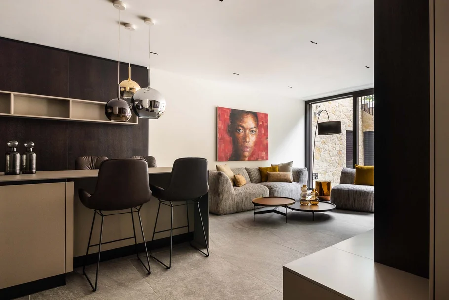 INTERIOS. Dein Interior-Design-Studio. Modernes Wohnzimmer mit Stühlen, Teppich, Kunst an der Wand und großen Fenstern