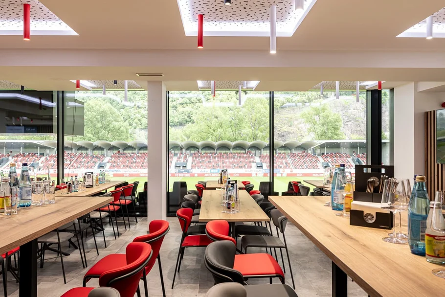 INTERIOS. Dein Interior-Design-Studio. Innenansicht eines modernen Restaurants mit Blick auf ein Fußballstadion