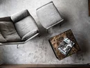 INTERIOS. Dein Interior-Design-Studio. Grauer Sessel und Hocker neben quadratischem Marmor-Couchtisch mit Zeitschrift