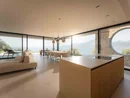 INTERIOS. Dein Interior-Design-Studio. Modernes Wohnzimmer mit Küche, Esstisch und Panoramablick auf See und Berge