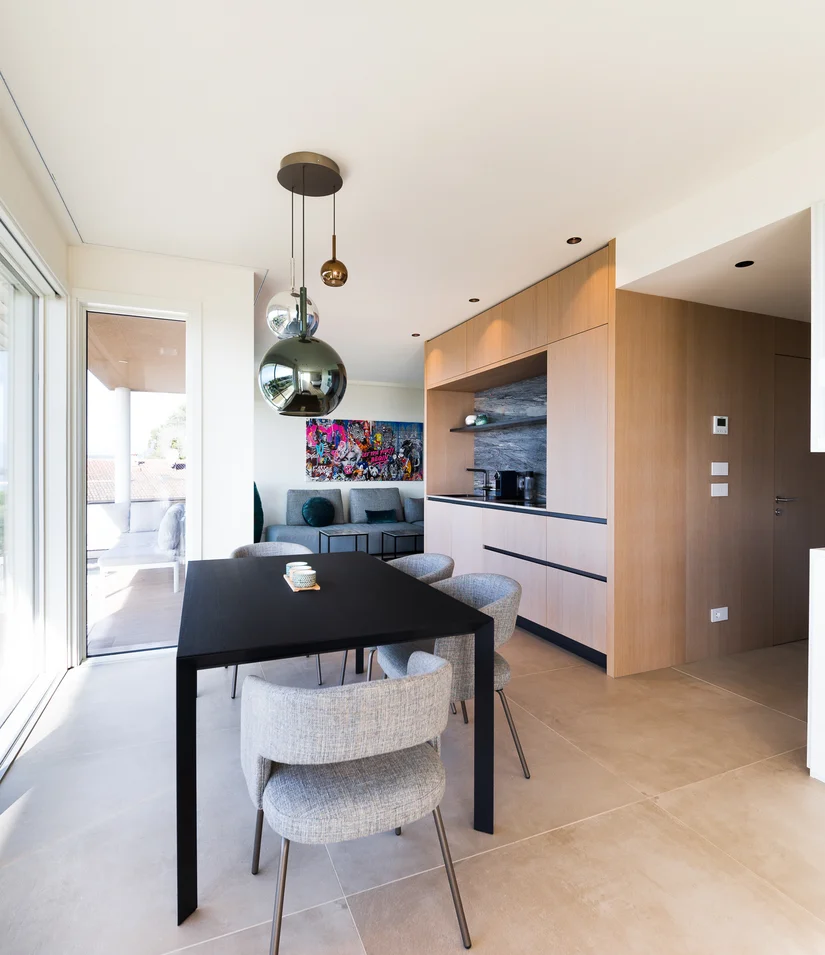 INTERIOS. Dein Interior-Design-Studio. Moderner Essbereich mit schwarz Tisch, grauen Stühlen und großem Fenster zur Terrasse